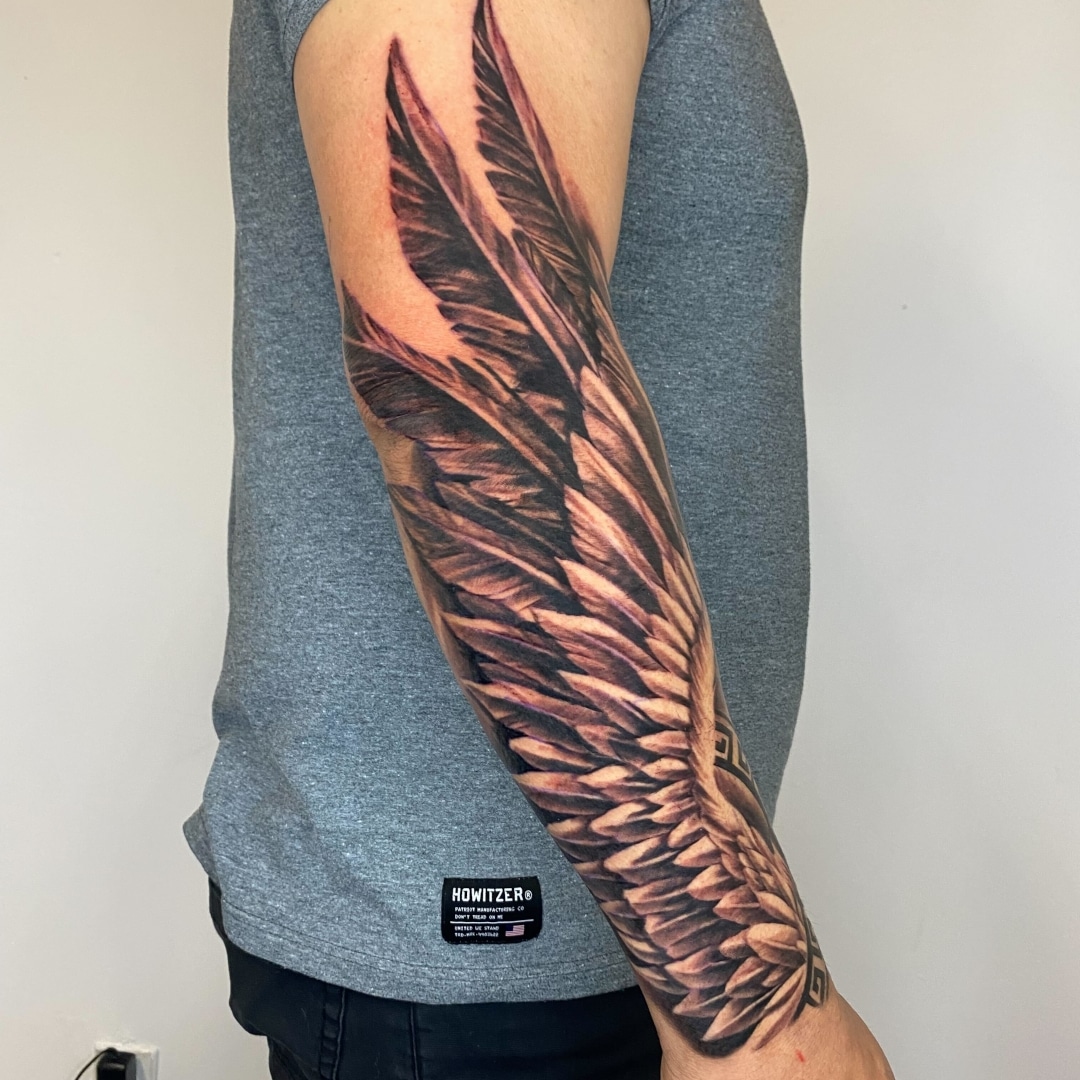 Detailed tattoo of angel wings on a forearm