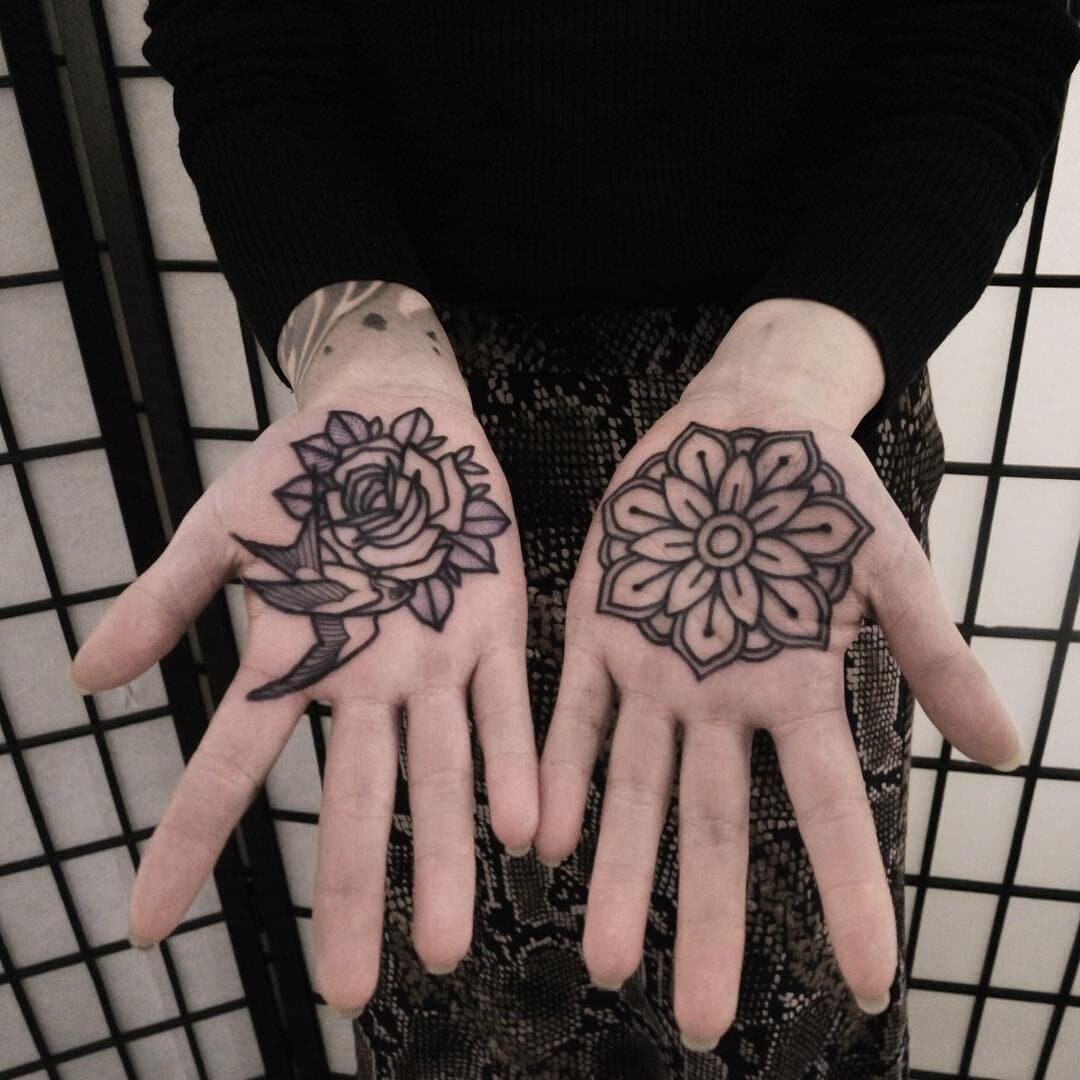 Two hands with floral tattoos, one with a rose and the other with a flower pattern.