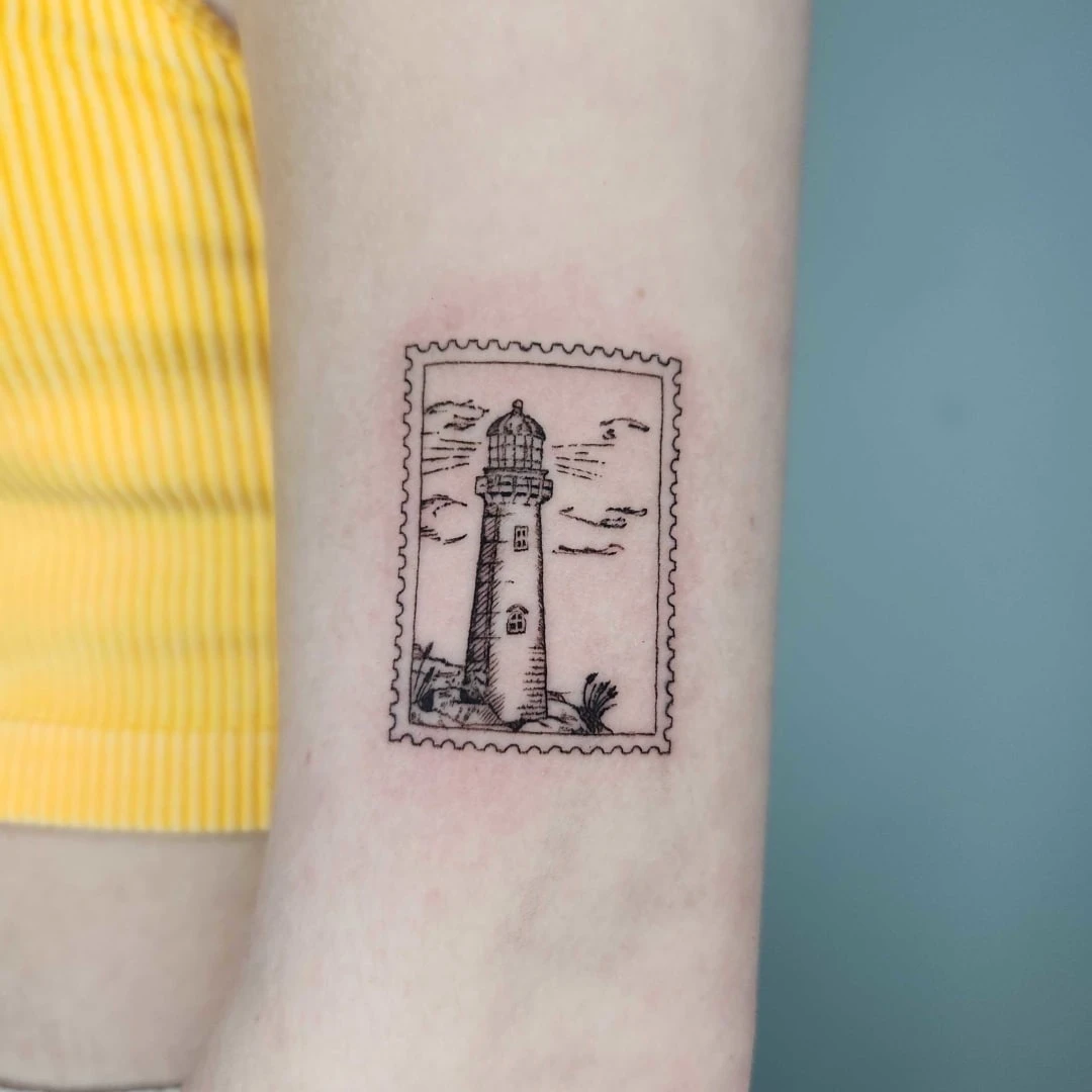 Tattoo of a lighthouse enclosed in a stamp design on arm