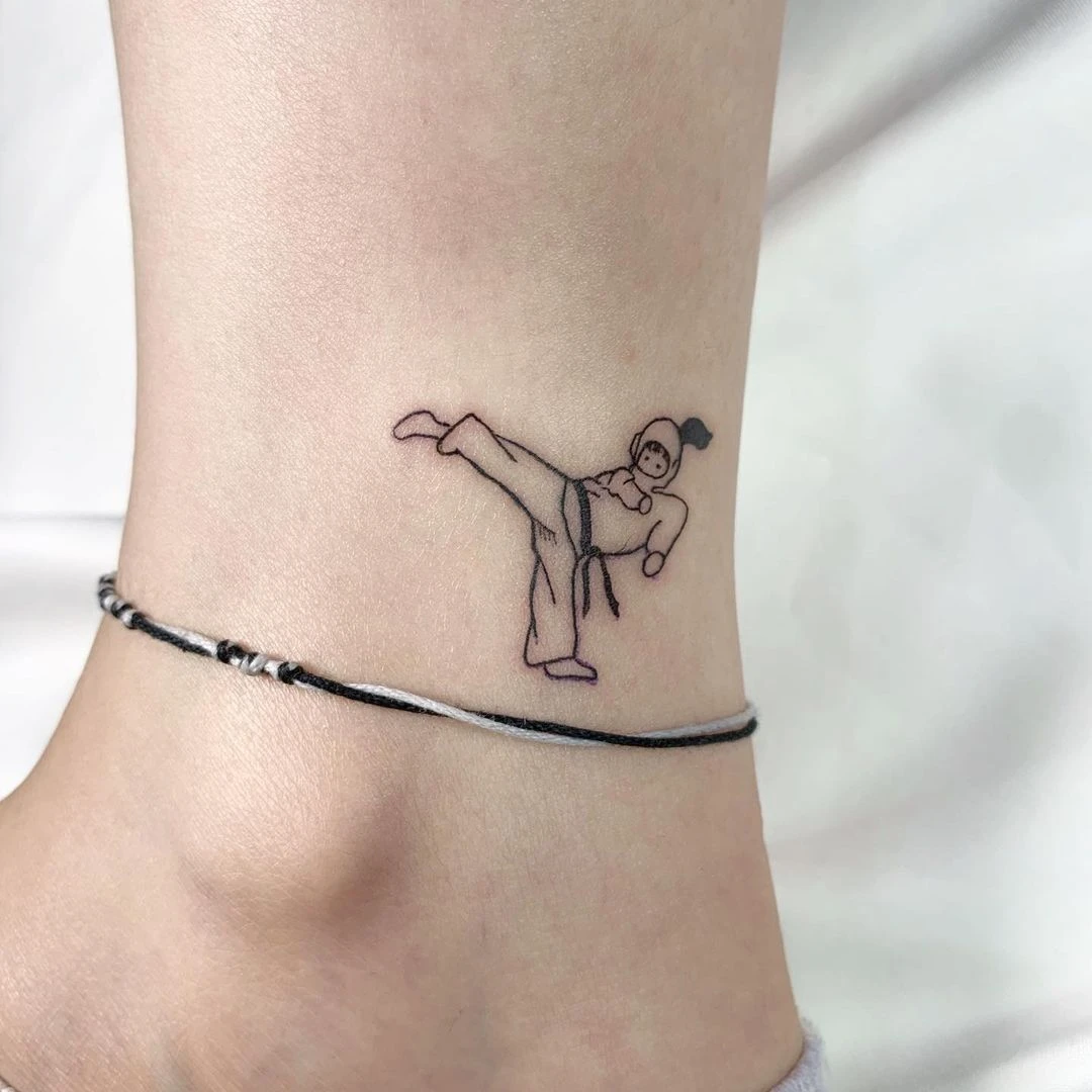 Tattoo of a martial artist kicking on a person's ankle.