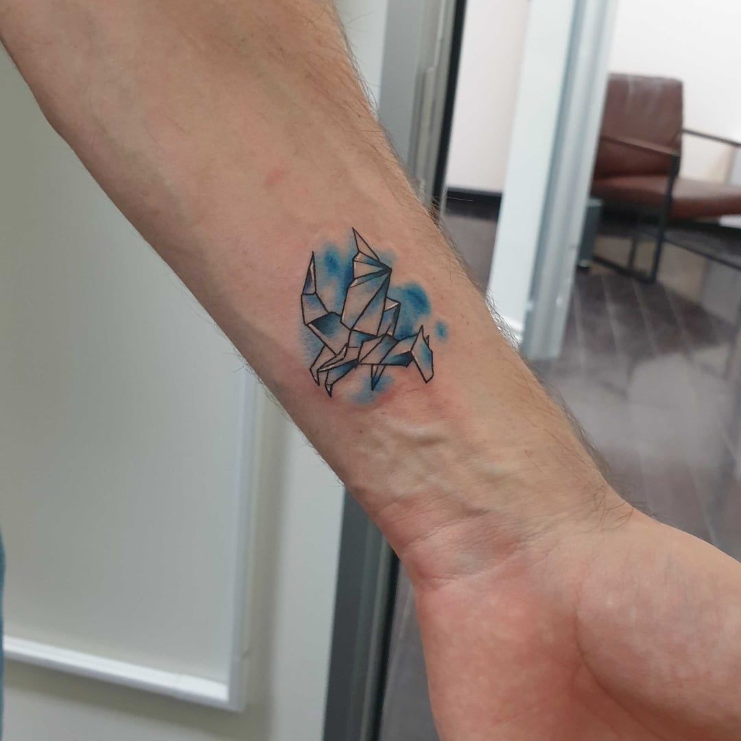 Origami tattoo design on an arm with blue accents