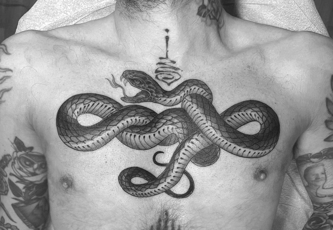 Black and grey snake tattoo on a man's chest.