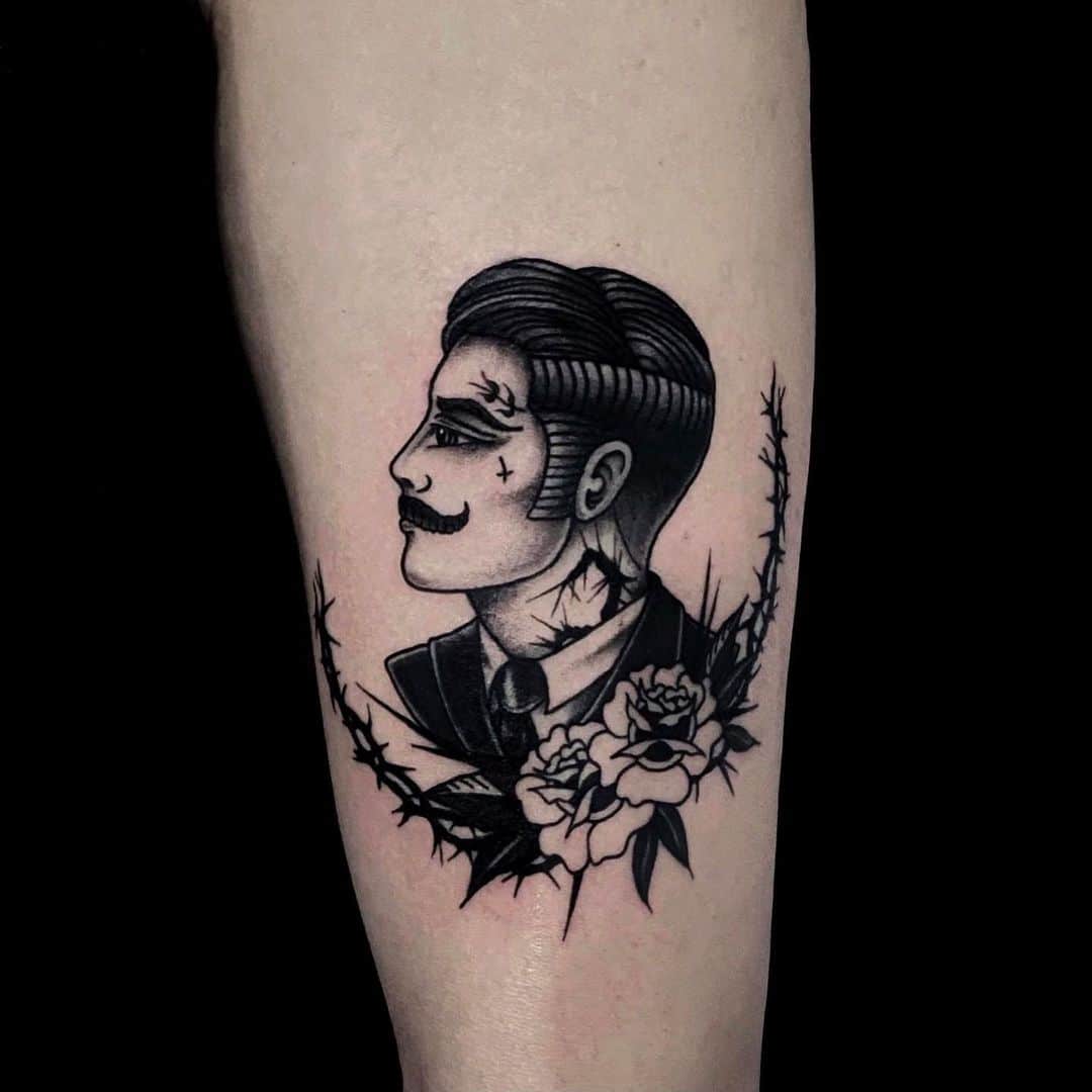 Black and grey tattoo of a man in a suit with flowers and thorns