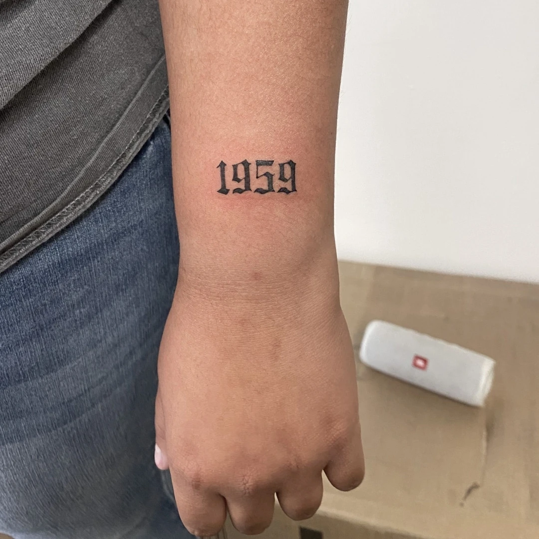 Tattoo on arm featuring the year 1959 in bold text