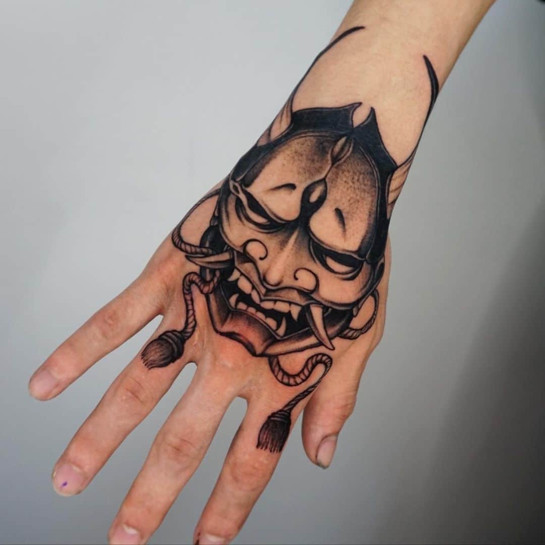 Intricate black and grey tattoo design on a hand.