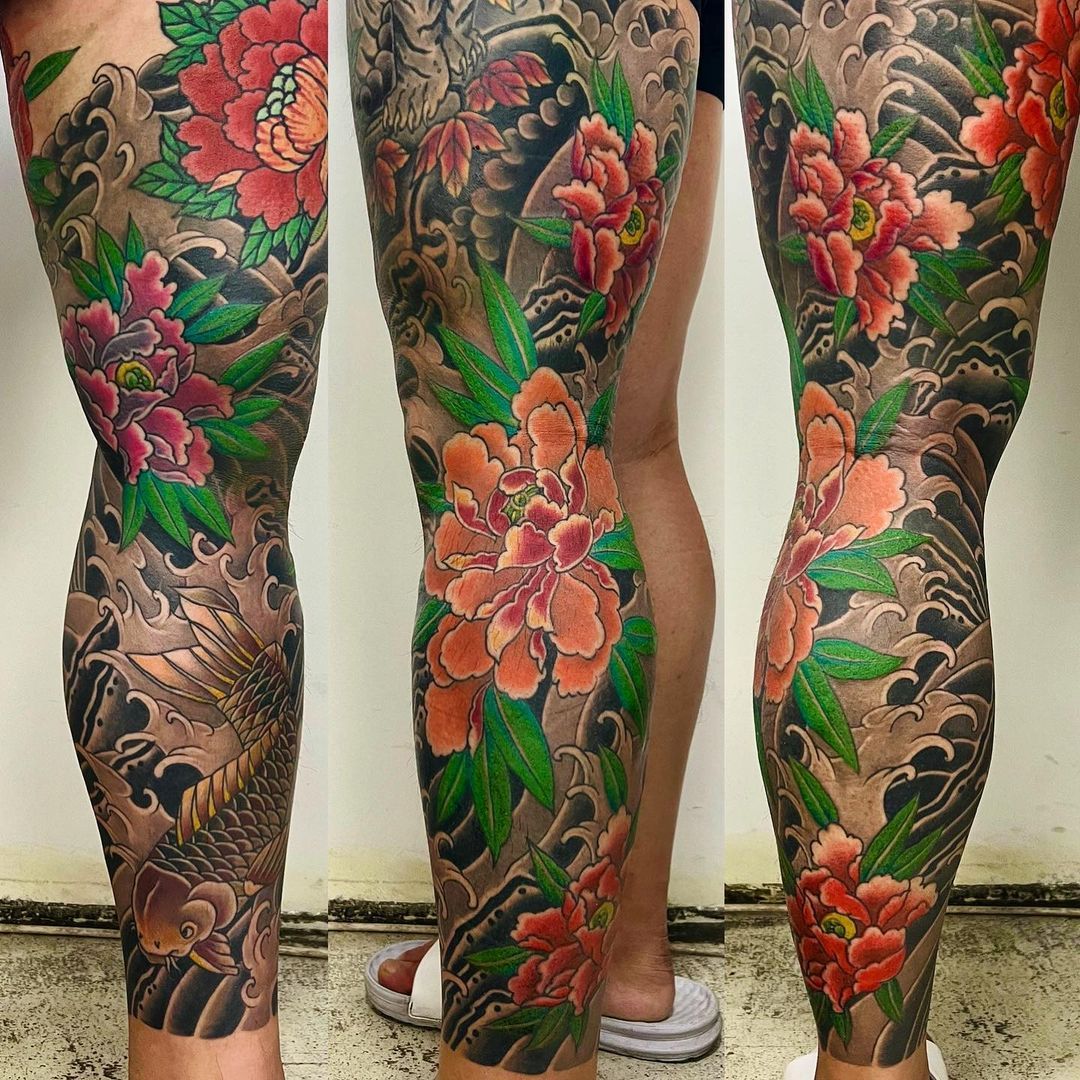 Vibrant tattoo art featuring floral and koi designs on legs.